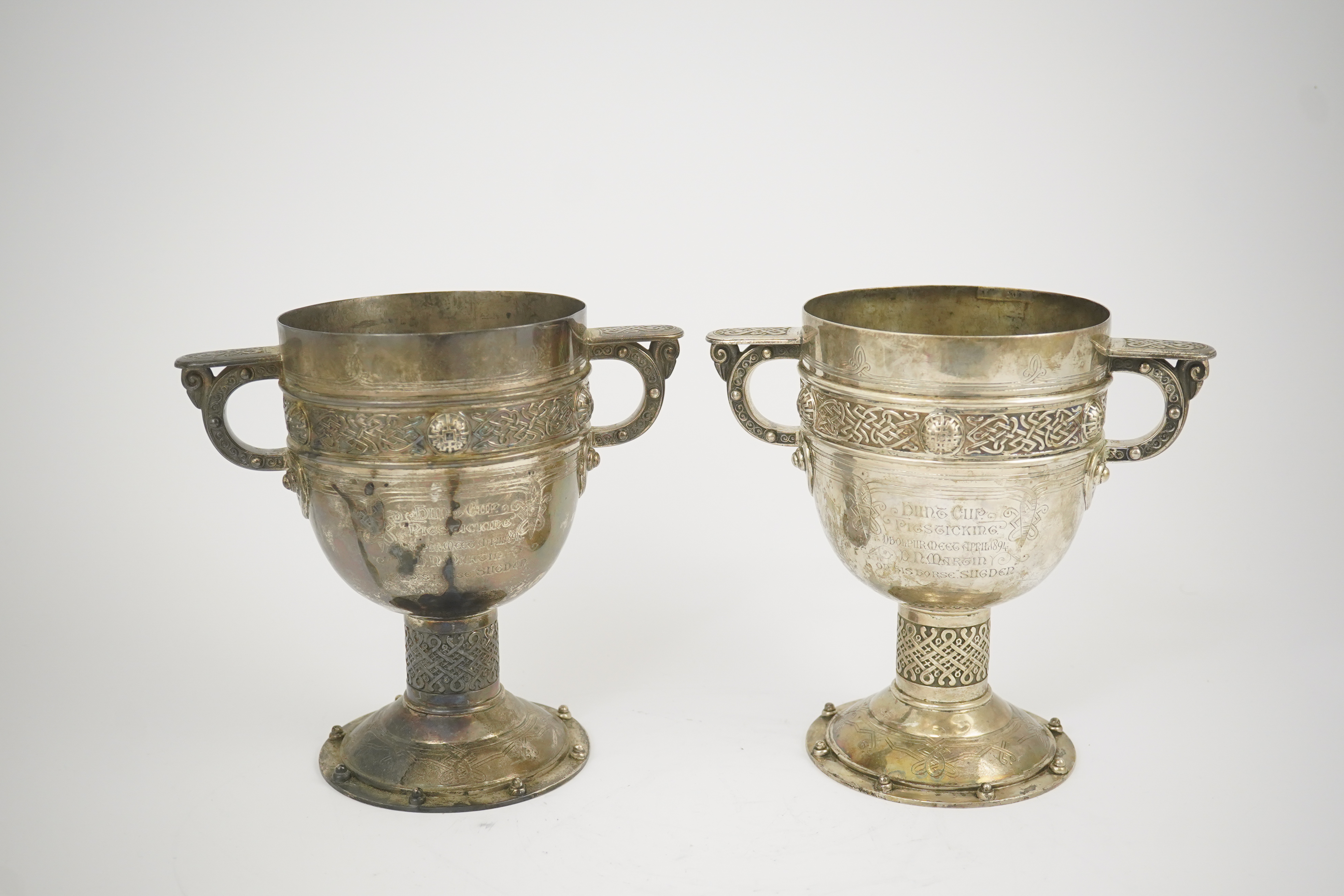 A pair of late Victorian Arts & Crafts Celtic style silver two handled presentation pedestal trophy cups, by Elkington & Co